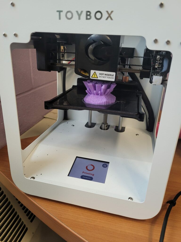 A 3D Printer prints a purple creation. 