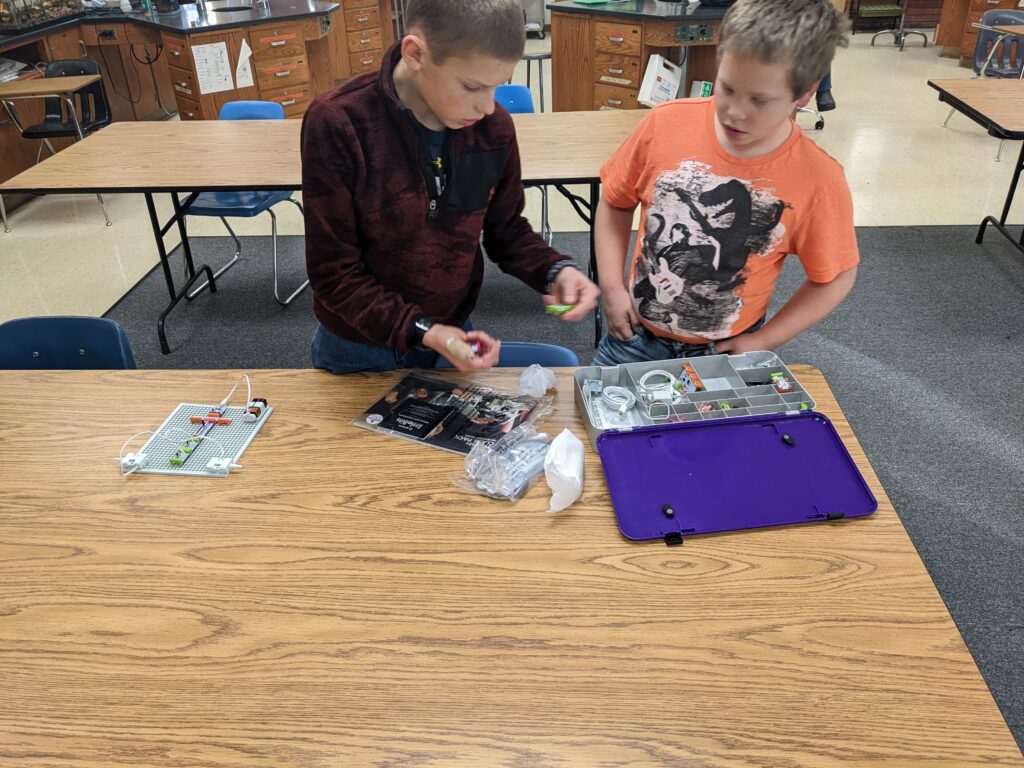 Two students sort through Little Bits pieces on a classroom table. 