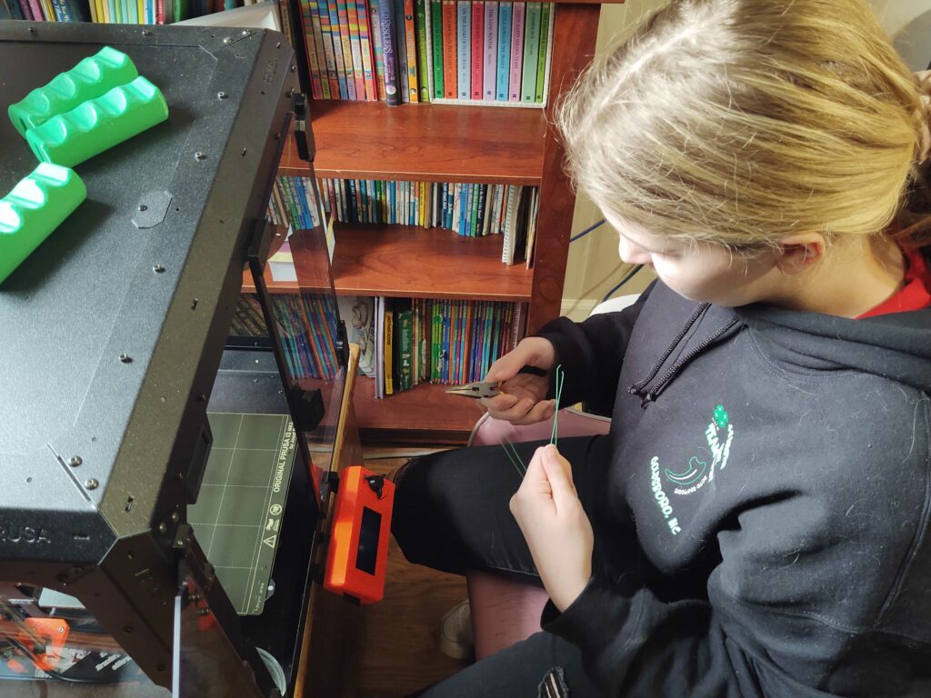 A team member works on the 3D printer in their home. 