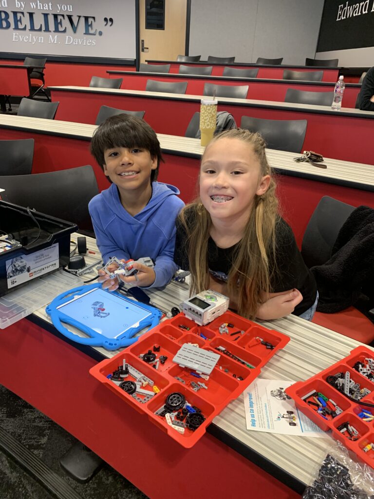 Students smile at a table with an iPad and robot pieces at Texas Tech University. 