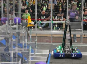 A robot places a cone on a node in a robotics competition.