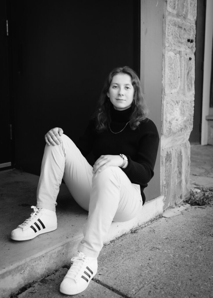 A black and white photo of Brooke, sitting outdoors. 