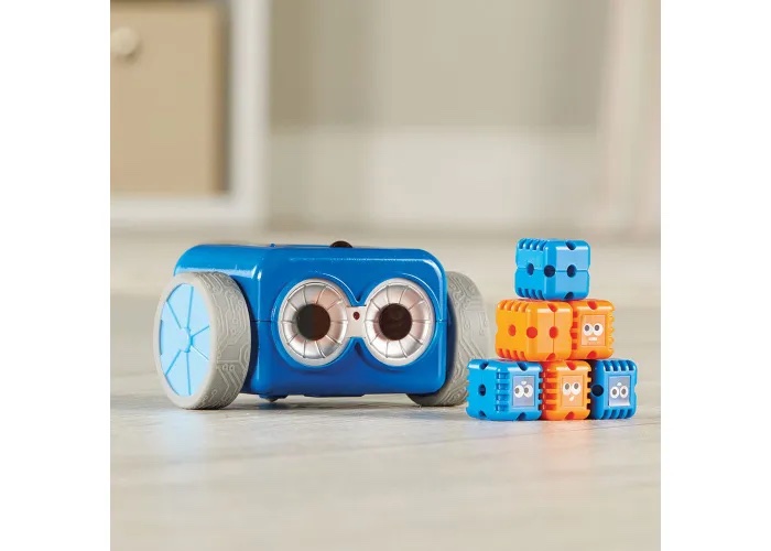 A Botley robot sits behind a tower of blue and orange obstacle building pieces.