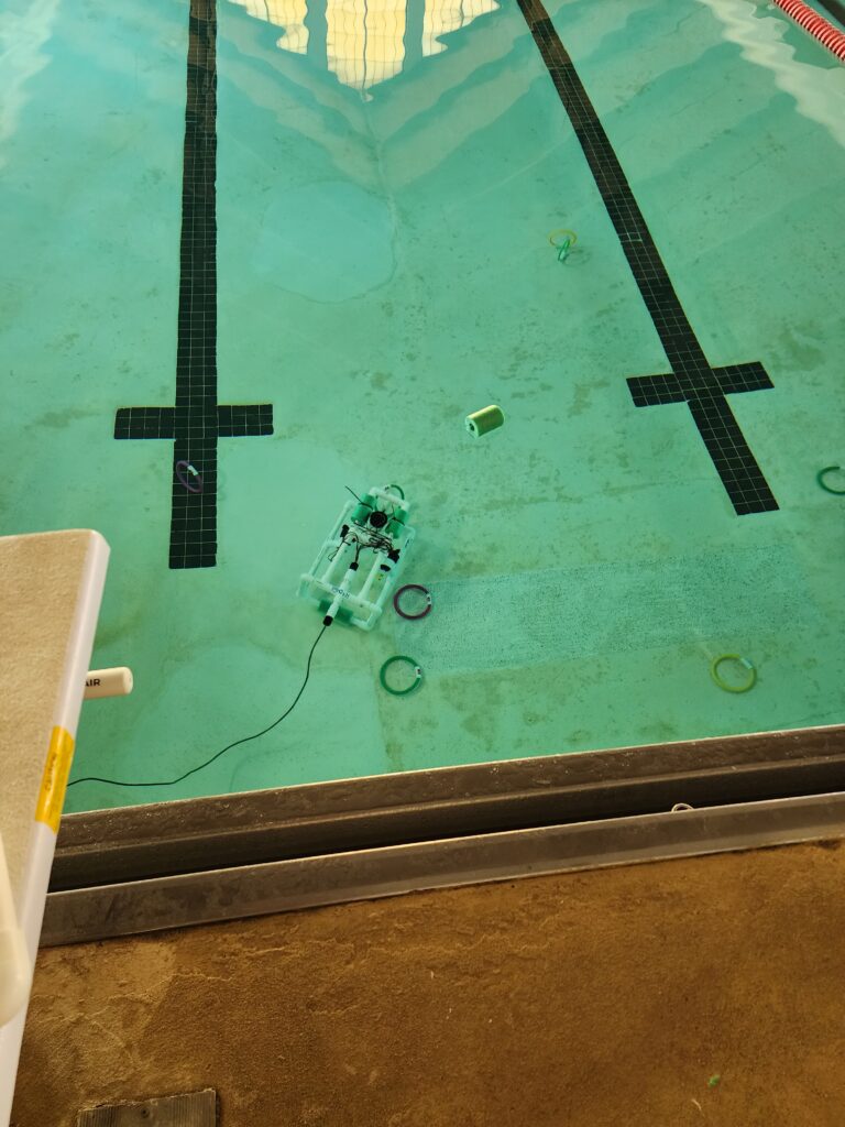 A robot sits at the bottom of a pool. 