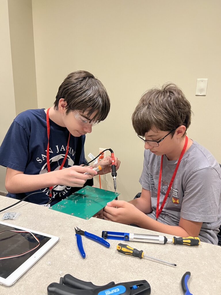 Two students carefully construct part of their robot. 