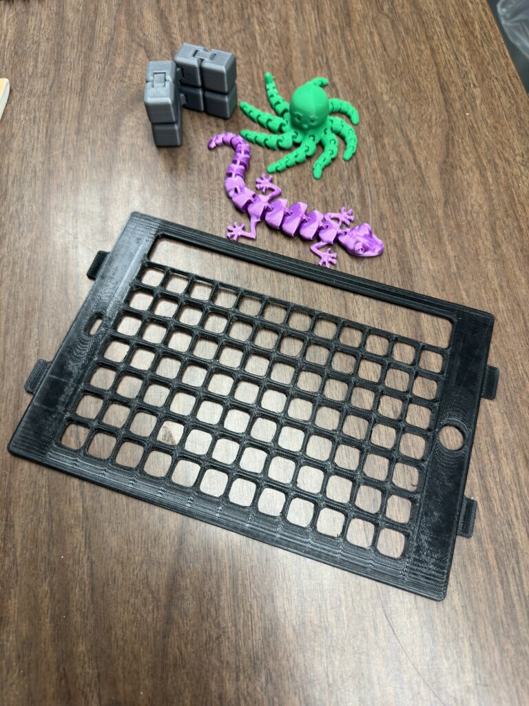 A 3D printed keyguard and fidget toys sit on a table, created by other classes for students within the school. 