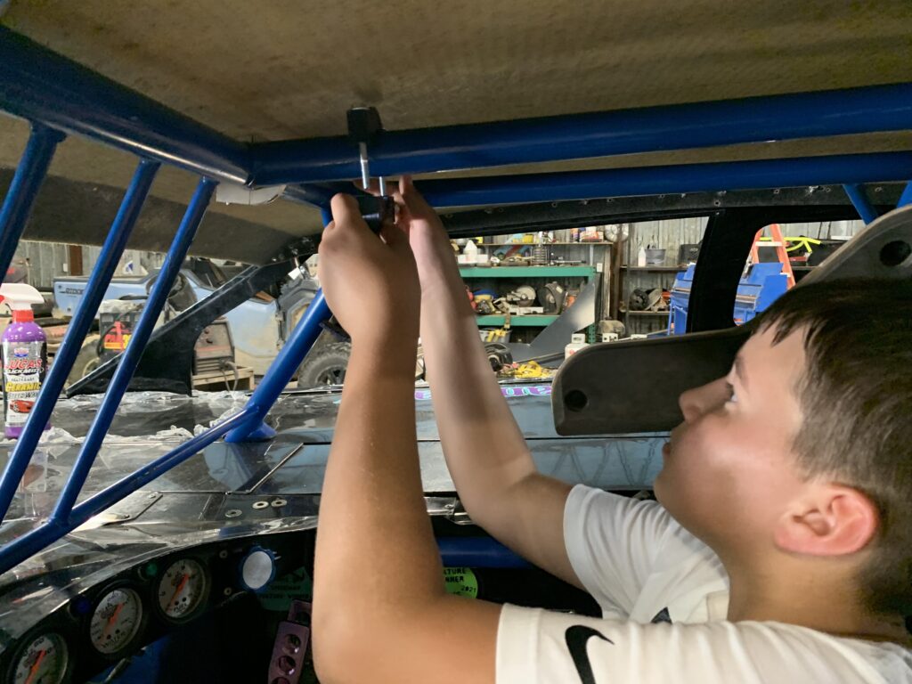 A student installs a 3D printed piece into a car for the county fair. 