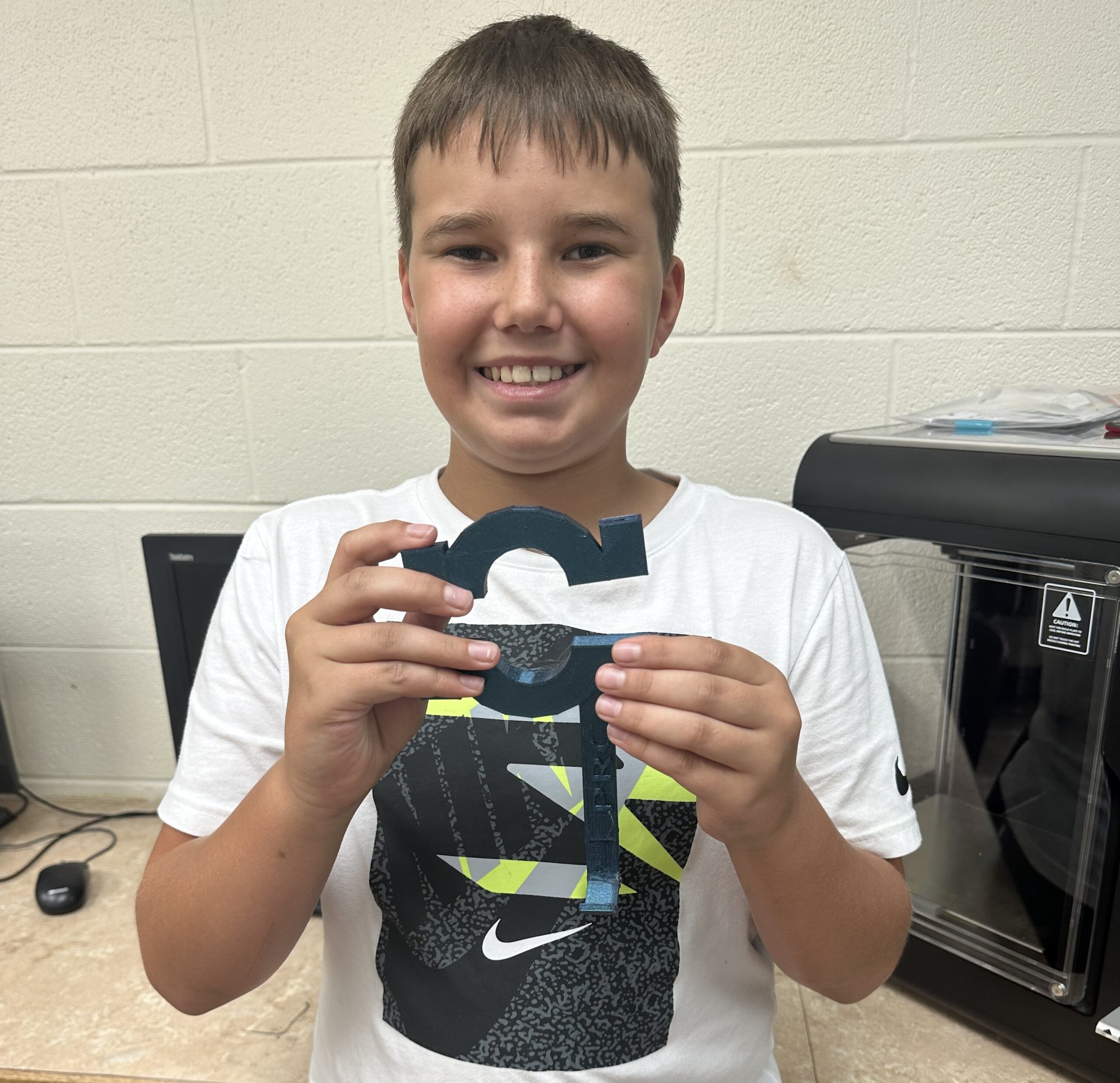 A student from Tuskahoma Public School holds up his 3D printed part for a county fair entry.