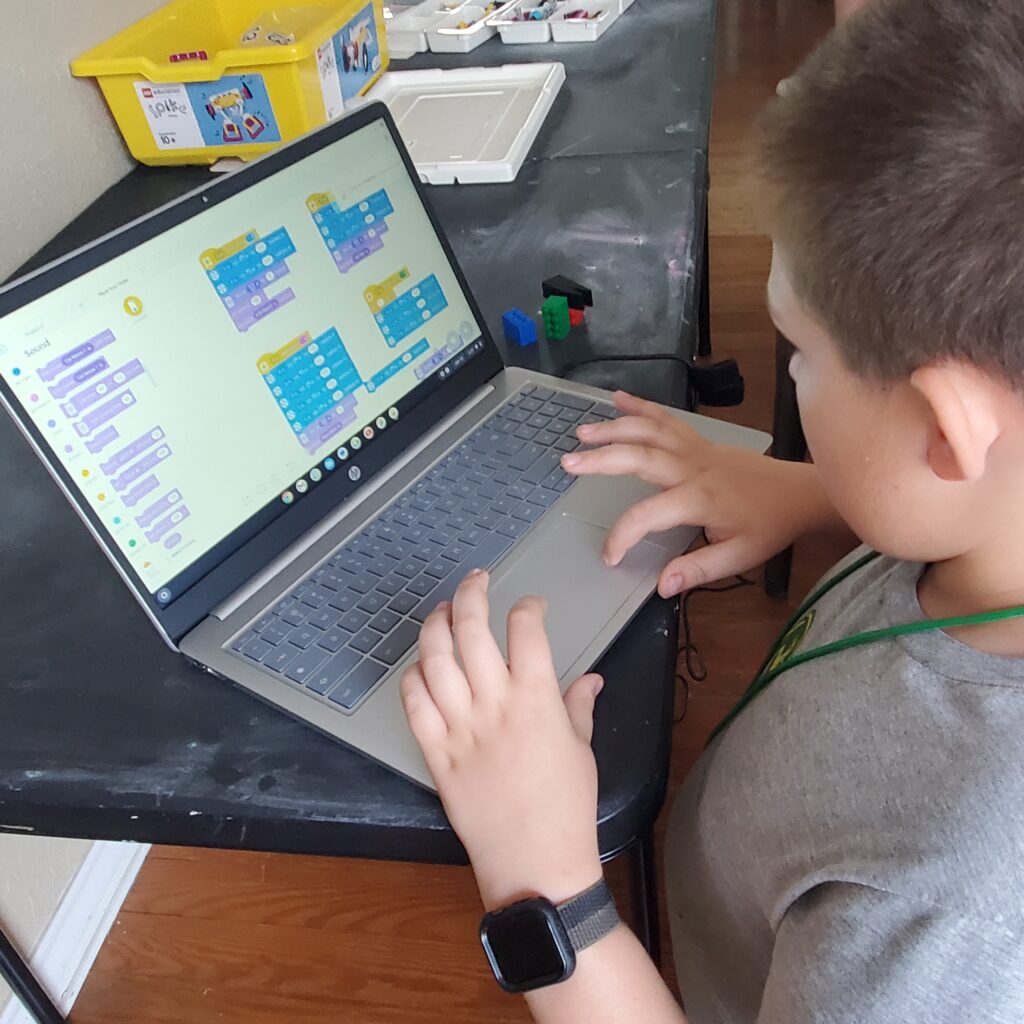 A student works on coding a LEGO Spike on his Chromebook. 