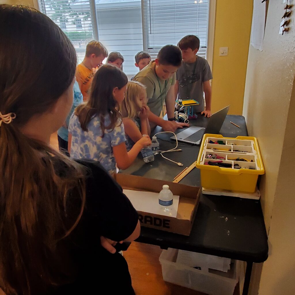 Students gather around a table with LEGO Spike parts and a Chromebook. 