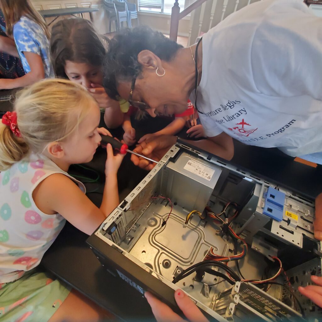 A student helps assemble pieces back on to a computer. 