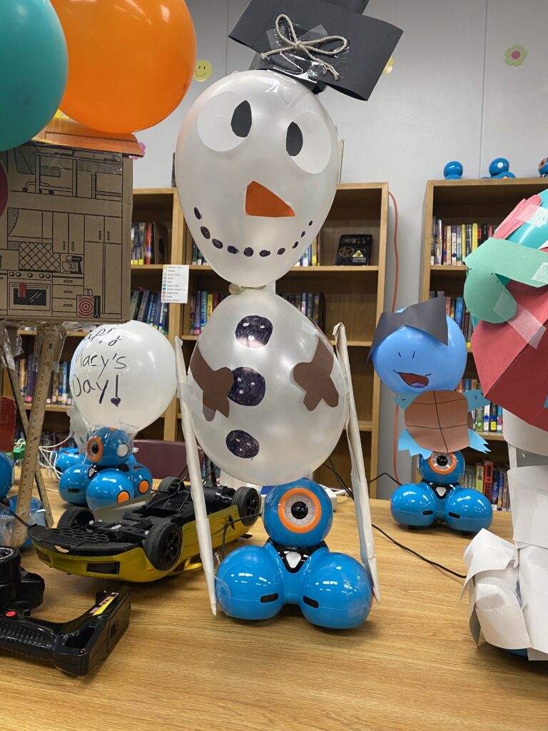 A snowman balloon float sits atop a Dash robot, centered among a crowd of other robot float creations. 