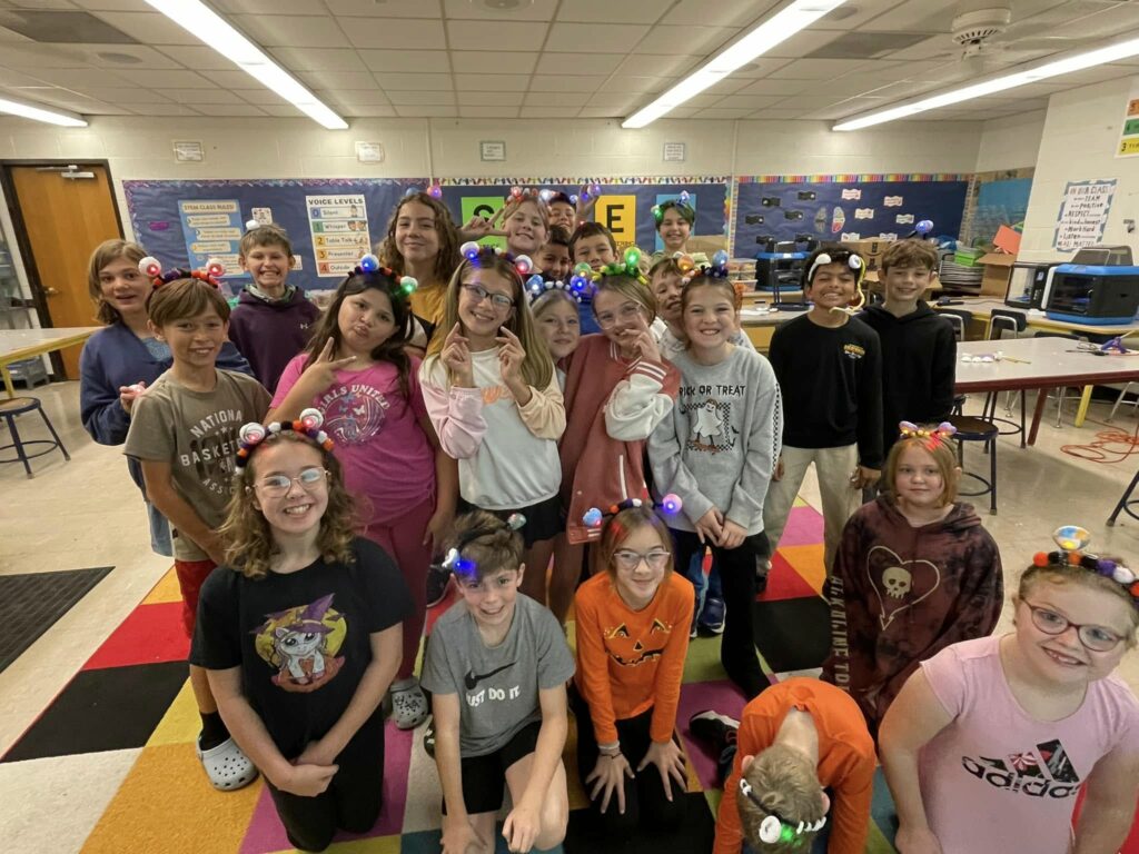 A group of students smiles and poses with their monster circuit headbands. 