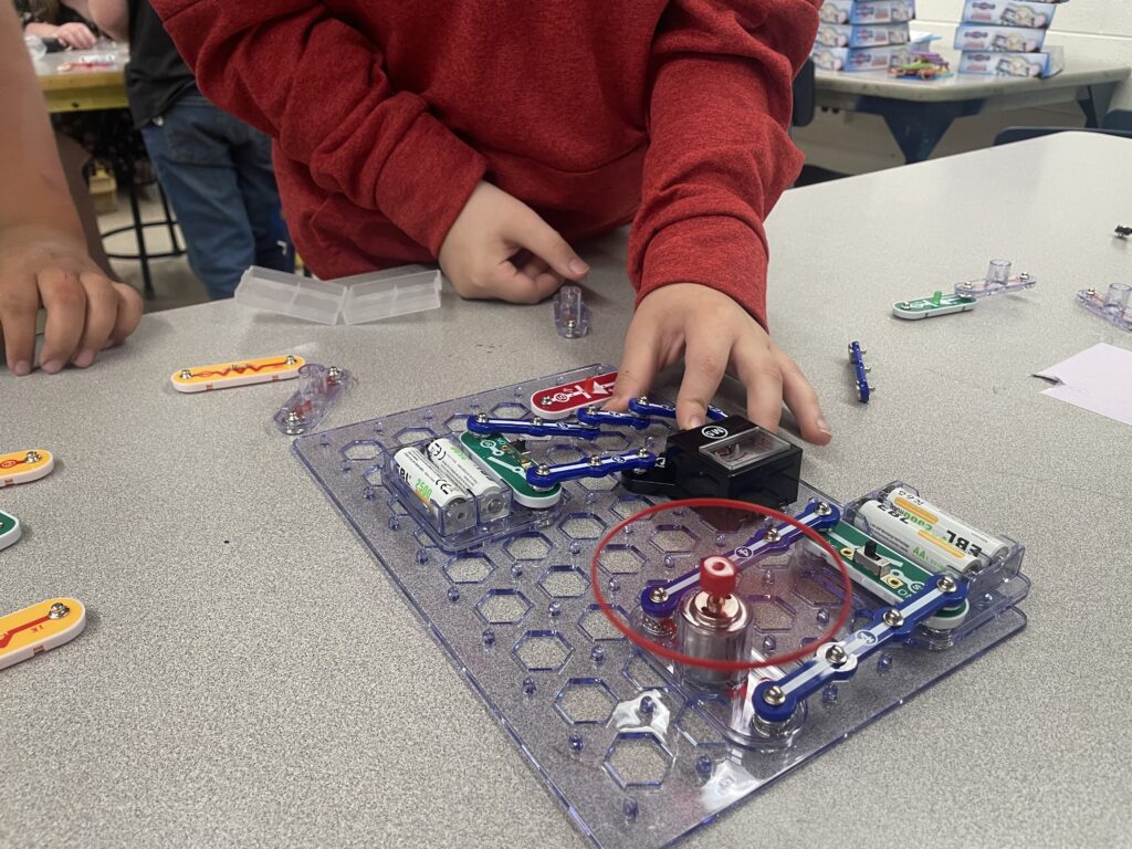 A student experiments with connecting Snap Circuits at a classroom table. 