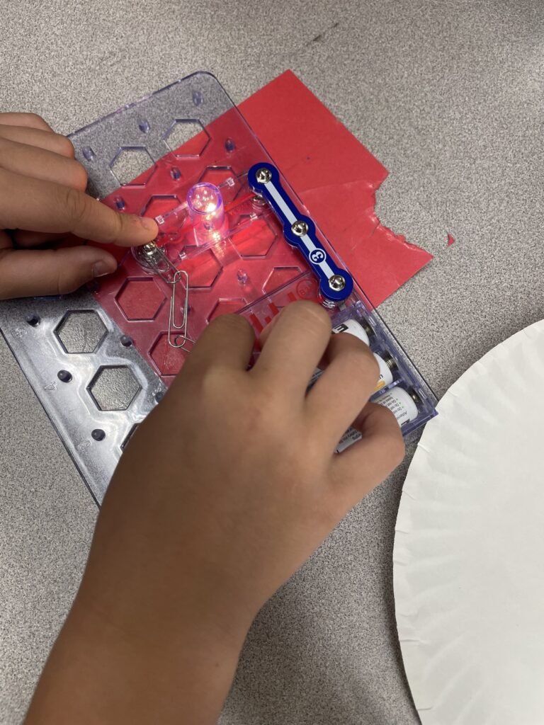 A student assembles a Snap Circuit that turns on a light bulb! 