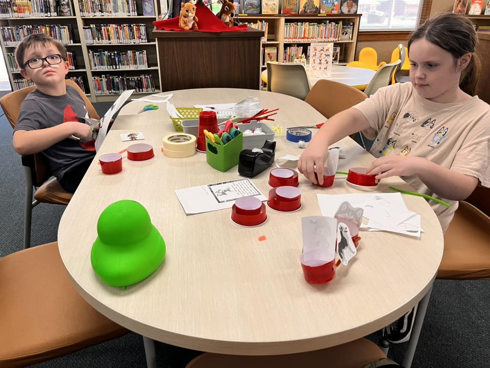 Students work on assembling their sleds for the Santa's Reindeer Sled Mission, using plastic cups, markers, paper, pipe cleaners, and more.