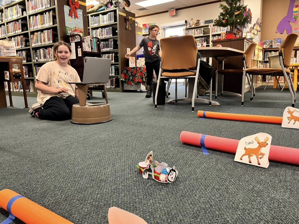 Patrons navigate their Spheros through the Santa's Reindeer Sled Mission, complete with pool noodle boundaries, reindeer cutouts, and sleds constructed for the Spheros.