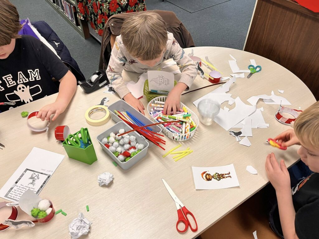 Students work on assembling their sleds for the Santa's Reindeer Sled Mission, using plastic cups, markers, paper, pipe cleaners, pom poms, and more.