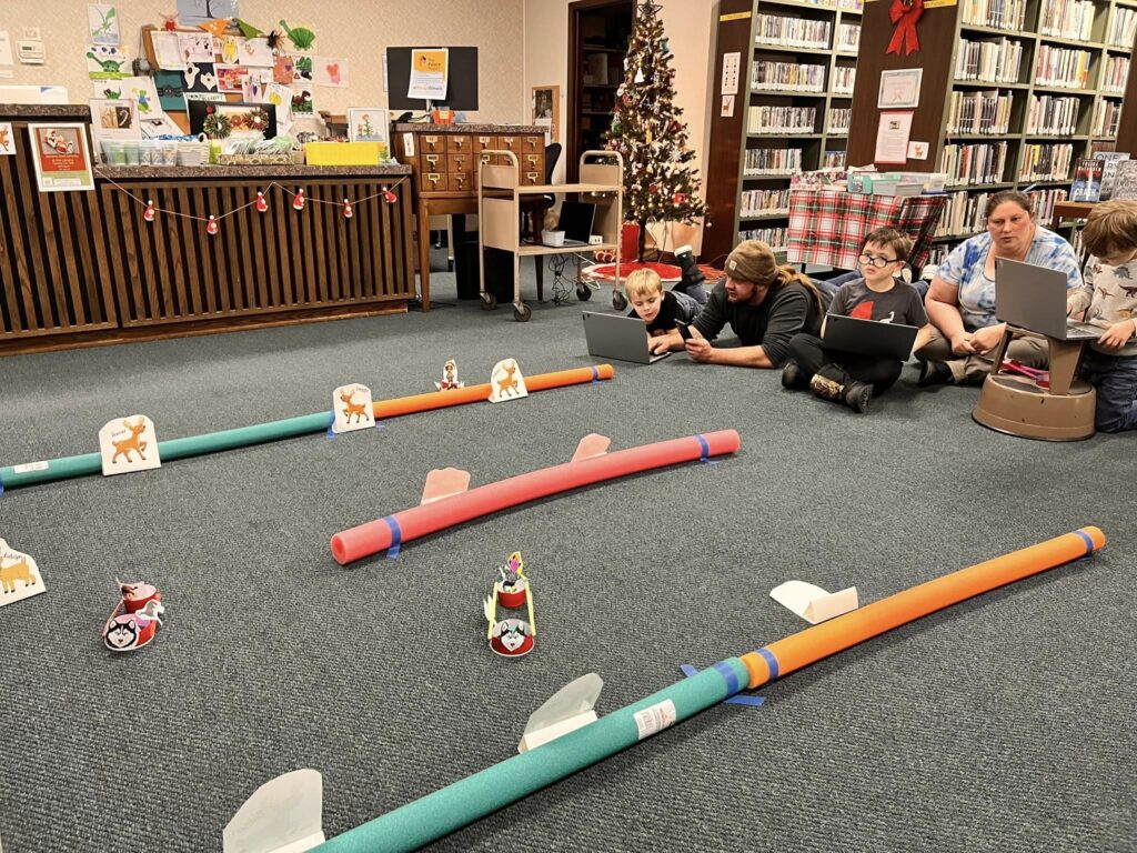 Patrons navigate their Spheros through the Santa's Reindeer Sled Mission, complete with pool noodle boundaries, reindeer cutouts, and sleds constructed for the Spheros.