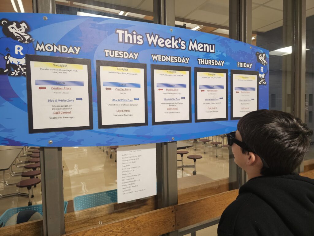 A student wearing Meta glasses reads the posted lunch menu at school. 