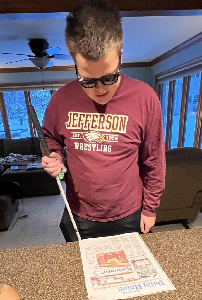 A student looks at the local newspaper with Meta Glasses on. 