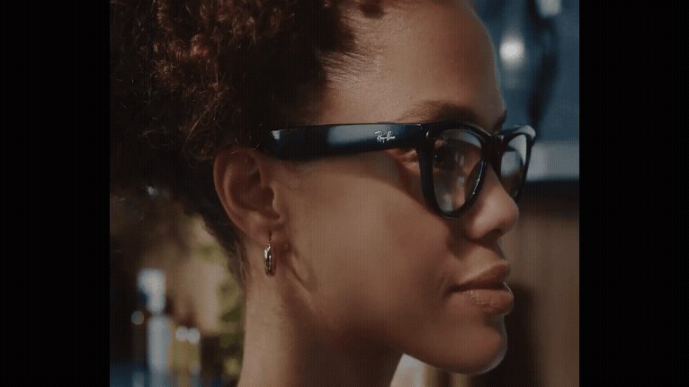 An individual slides their finger along the arm of the Meta glasses, demonstrating how to control the volume. 