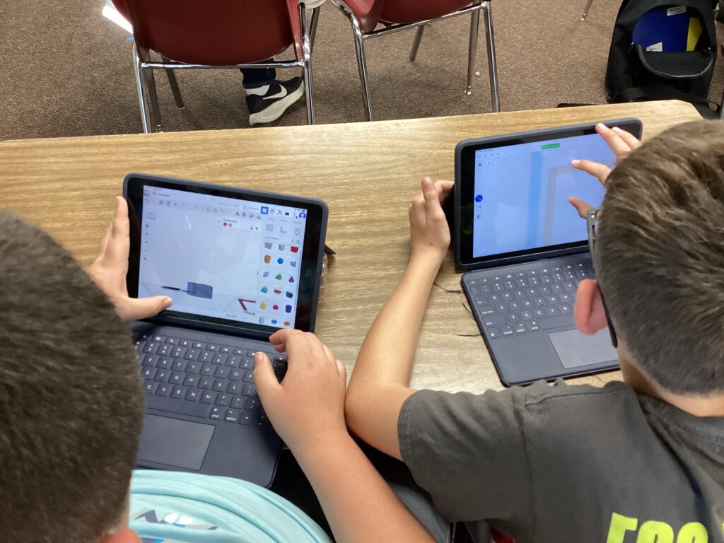 Two students work on designs on tablets. 