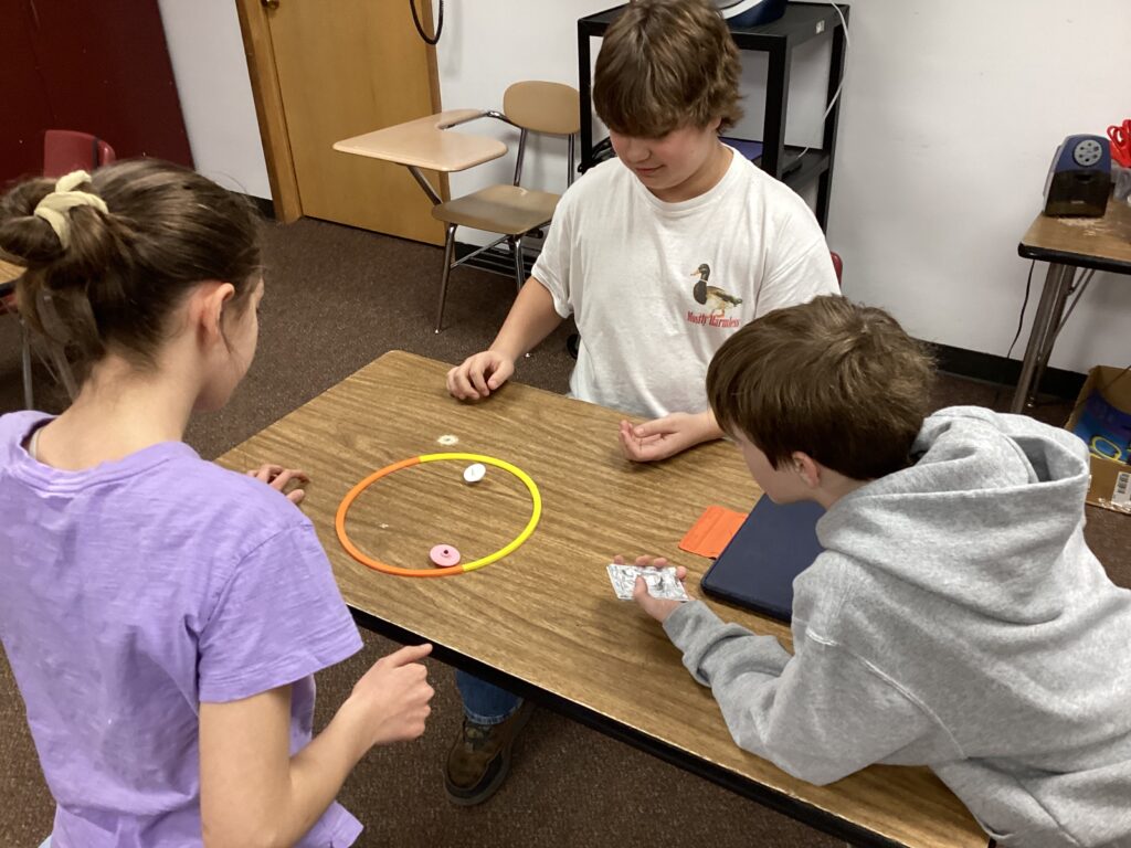 Students spin their 3D printed products on a classroom table. 