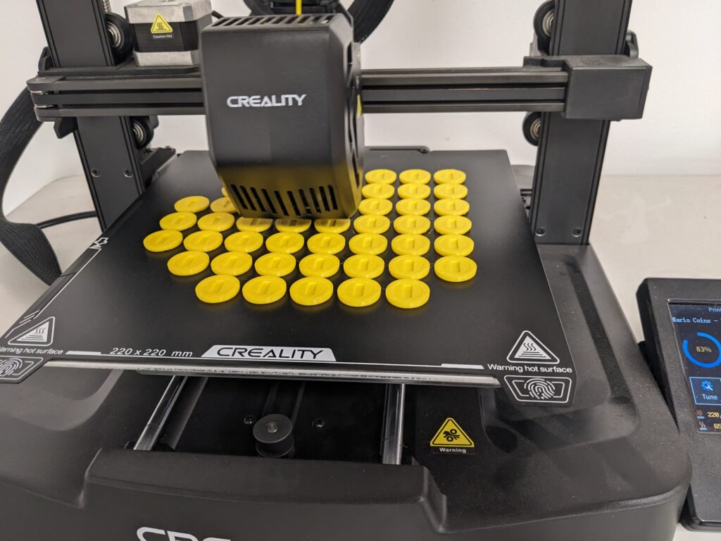 A close-up of the 3D printer printing rows of golden coins. 
