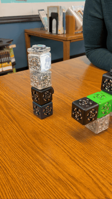 A Cubelet build with a spinning top at the Rolla Public Library event station, with another Cubelet build rolling by.