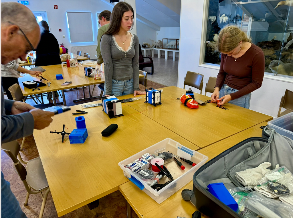 Individuals gather around a table, assembling pieces of their payloads to launch into the stratosphere.