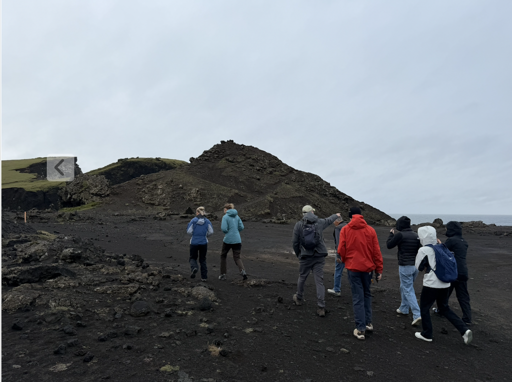 Some of the group walking along a dark, rocky landscape.