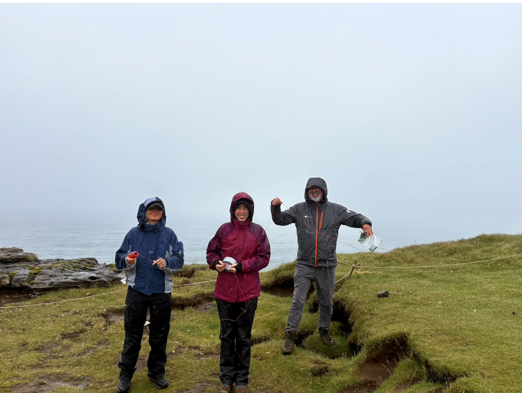 Three members of the team posing in rainy, foggy conditions prior to the launch.