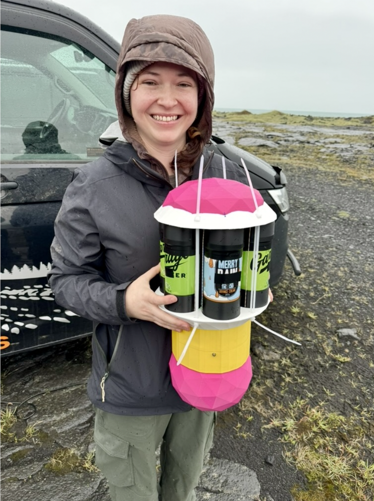 A student smiles, holding a brightly colored piece of the experiment, complete with decorative stickers.