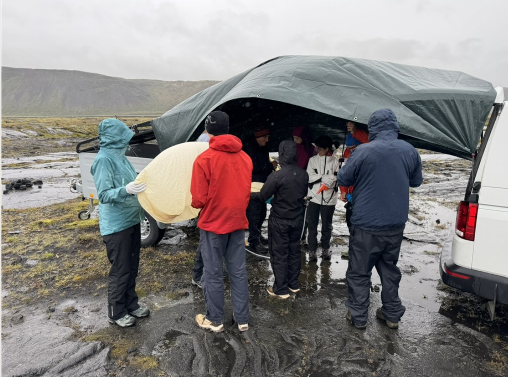 Individuals gather under a tarp, preparing the balloon for launch.