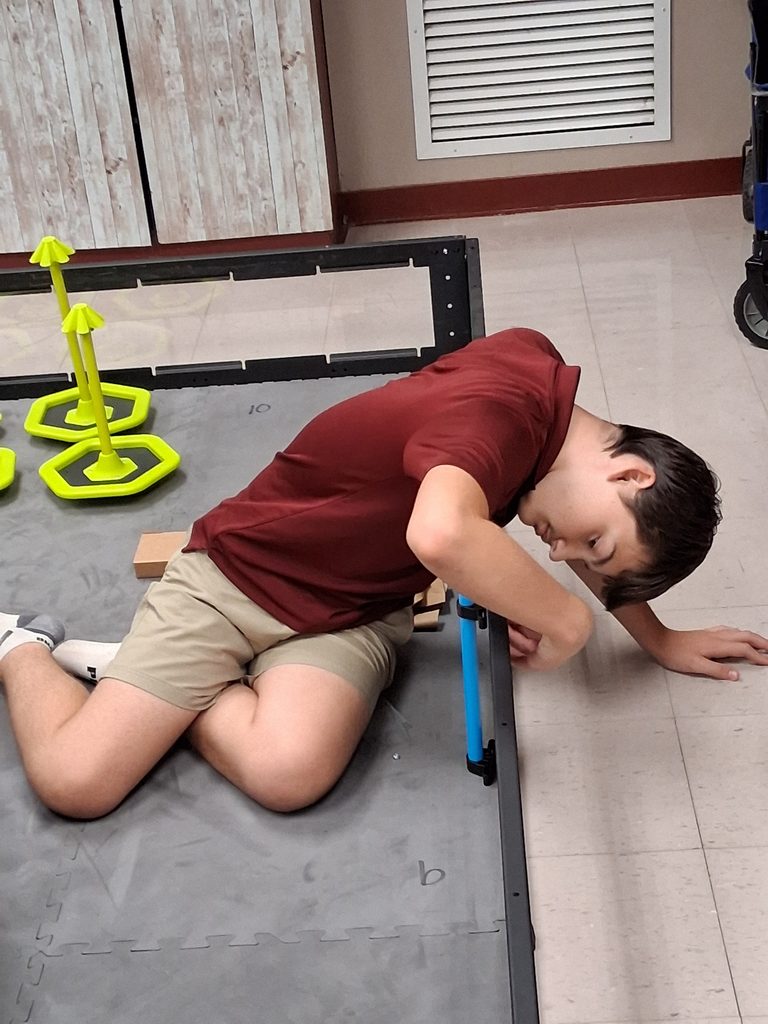 A student works on the competition mat on the classroom floor.
